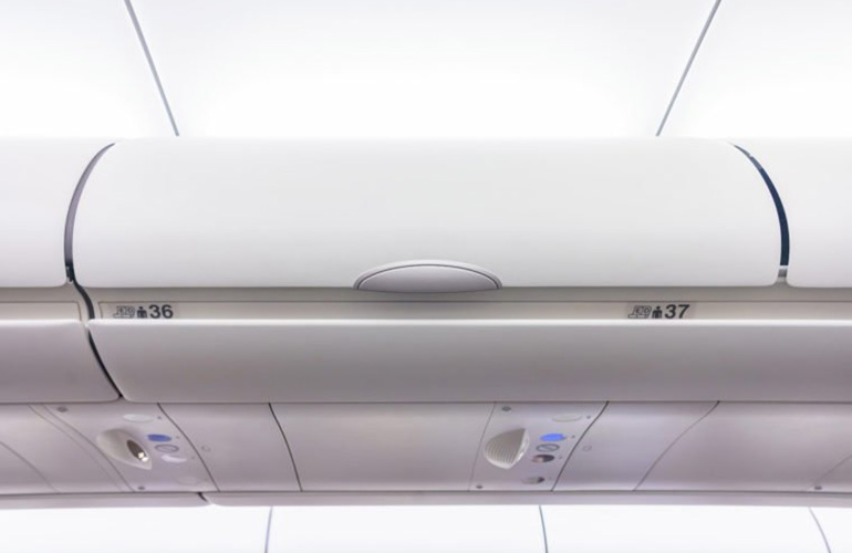 Why do flight attendants reach upwards as they walk?