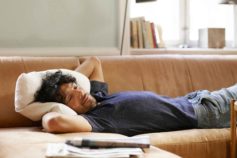 man lying on couch watching TV