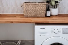 a laundry room with a washing machine, laundry bag, basket and flower