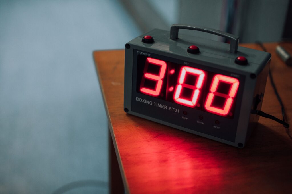 A red digital clock showing 3:00 on a bedside table