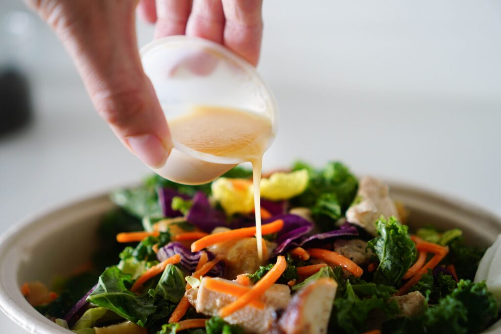 pouring dressing over a salad.