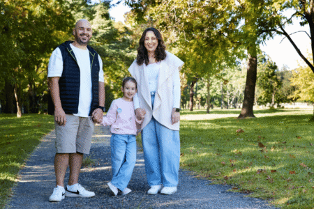 Family of three walking in a sunny park.