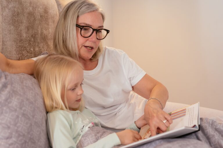 Grandmother reading a book with her young granddaughter.